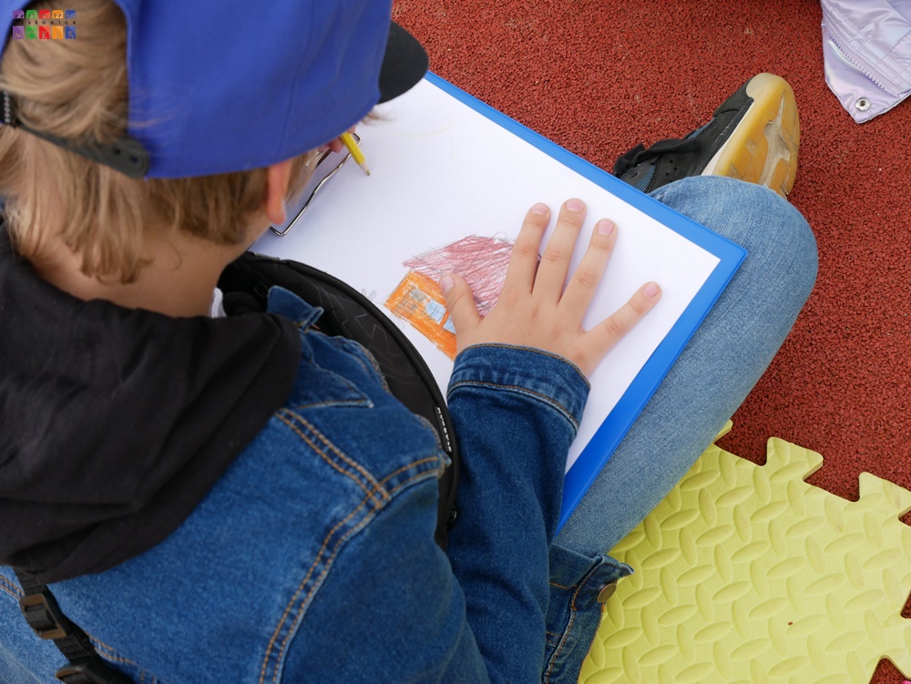 Zdjęcie przedstawiające rysujące dziecko na białej kartce papieru.
