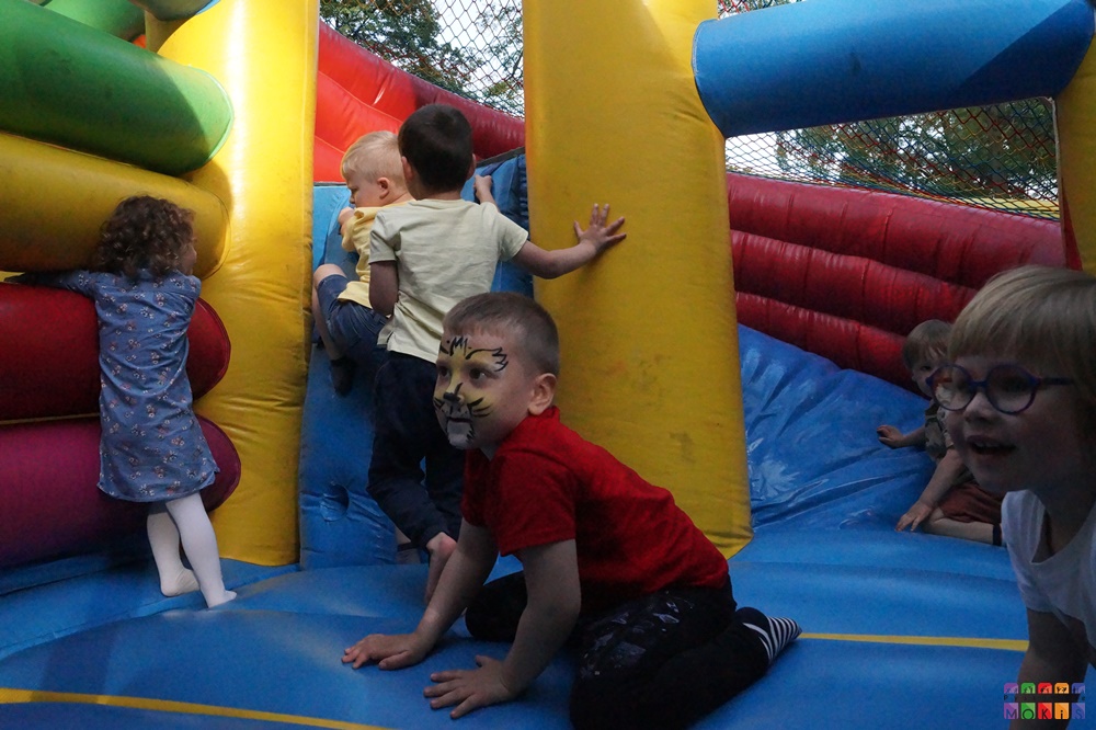 Zdjęcie przedstawiające dzieci bawiące się na kolorowym dmuchanym zamku.