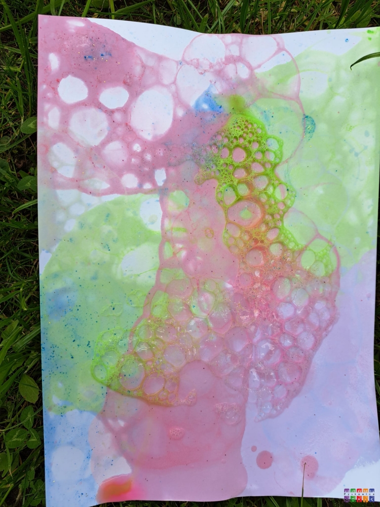Zdjęcie przedstawiające kartkę papieru z namalowanym, kolorowym obrazkiem z baniek mydlanych