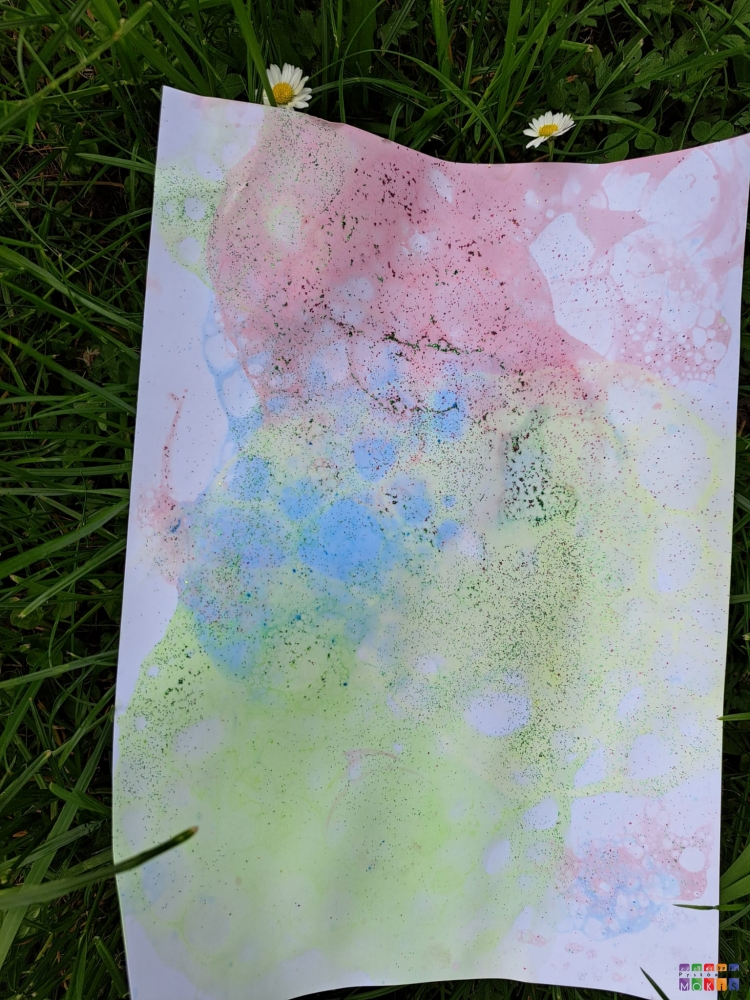 Zdjęcie przedstawiające kartkę papieru z namalowanym, kolorowym obrazkiem z baniek mydlanych