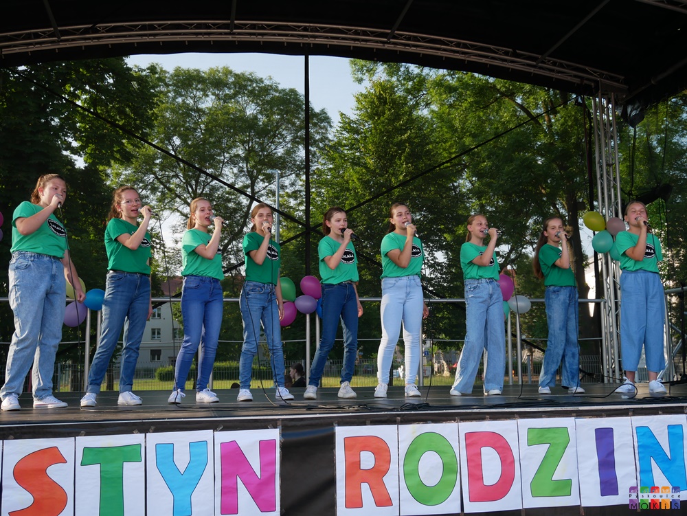 Zdjęcie przedstawiające tańczące i śpiewające dzieci i młodzież na scenie w trakcie festynu.