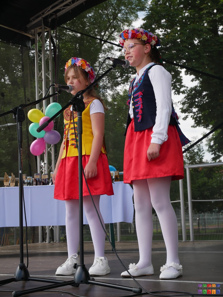 Zdjęci przedstawiające śpiewające dwie dziewczynki stojące przy mikrofonach