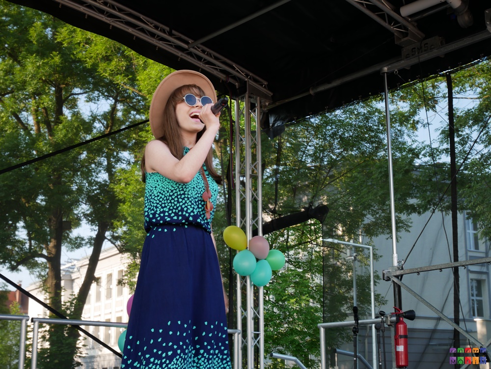 Zdjęcie przedstawiające śpiewającą dziewczynę do mikrofonu.