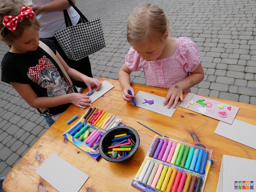 Zdjęcie przedstawia malujące na kartkach dzieci