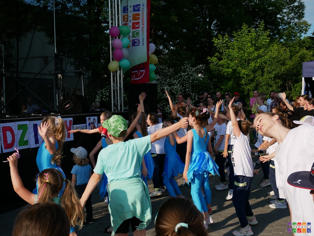 Zdjęcie przedstawiające tańczącą młodzież i dzieci w trakcie festynu na dziedzińcu MOKiS