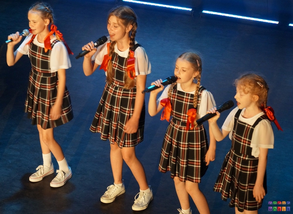 Zdjęcie przedstawia śpiewającą młodzież oraz dzieci na scenie w sali widowiskowej MOKiS Pyskowice