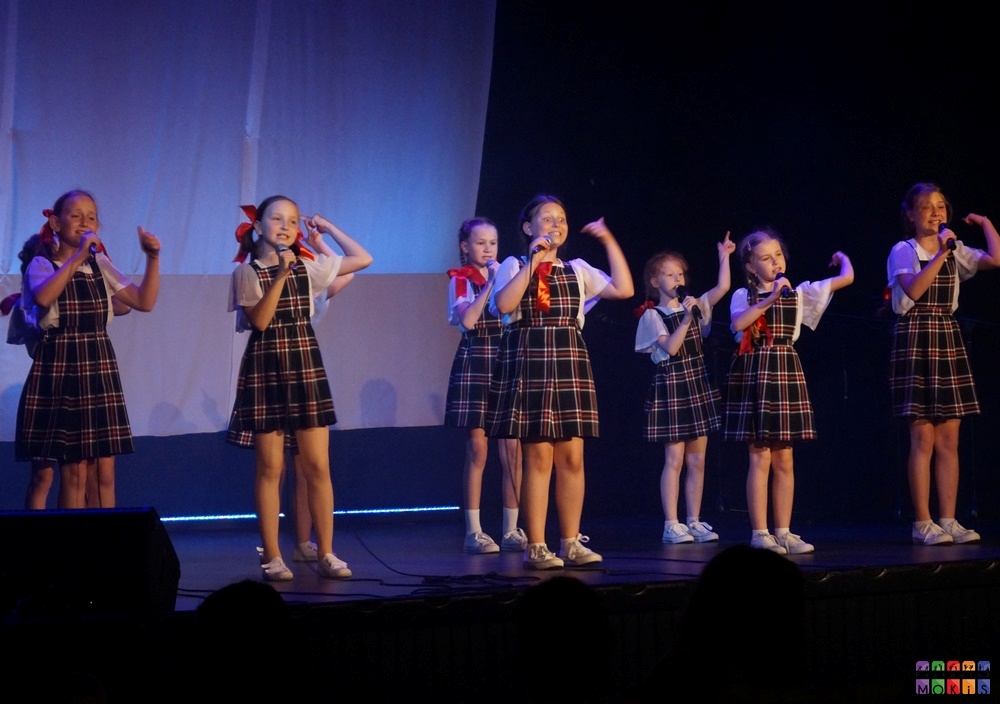 Zdjęcie przedstawia śpiewającą młodzież oraz dzieci na scenie w sali widowiskowej MOKiS Pyskowice
