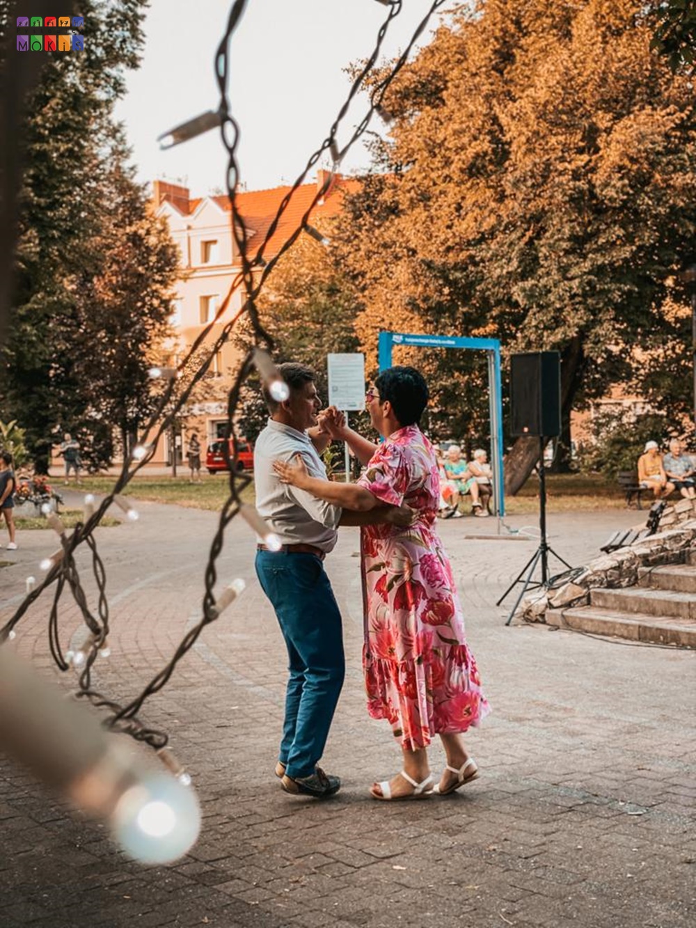 Zdjęcie przedstawiające tańczących ludzi w parku. W tle widać drzewa parkowe.