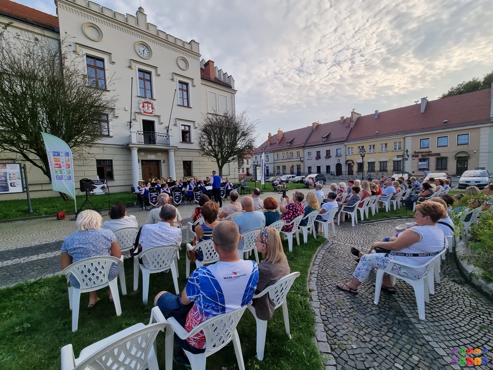 Zdjęcie przedstawia grającą orkiestrę dentą przed Ratuszem w Pyskowicach oraz siedzących ludzi