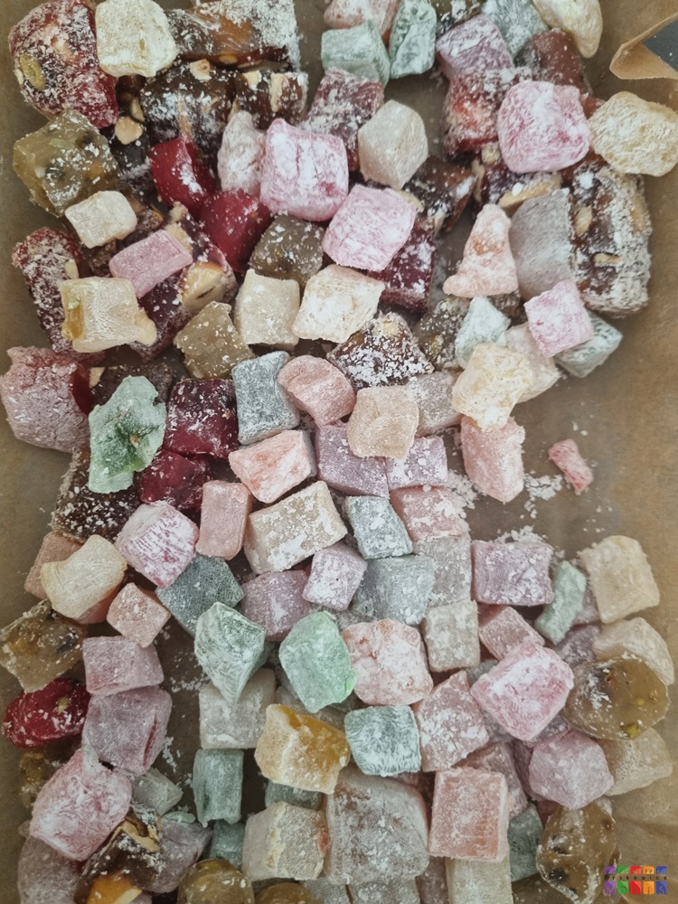 Zdjęcie przedstawia rozsypane kawałki cukierków w różnych kolorach