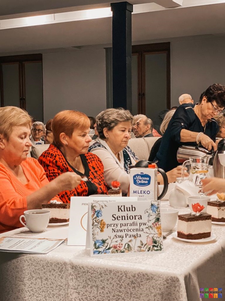 Zdjęcie przedstawiające siedzących seniorów przy stolikach w sali widowiskowej MOKiS