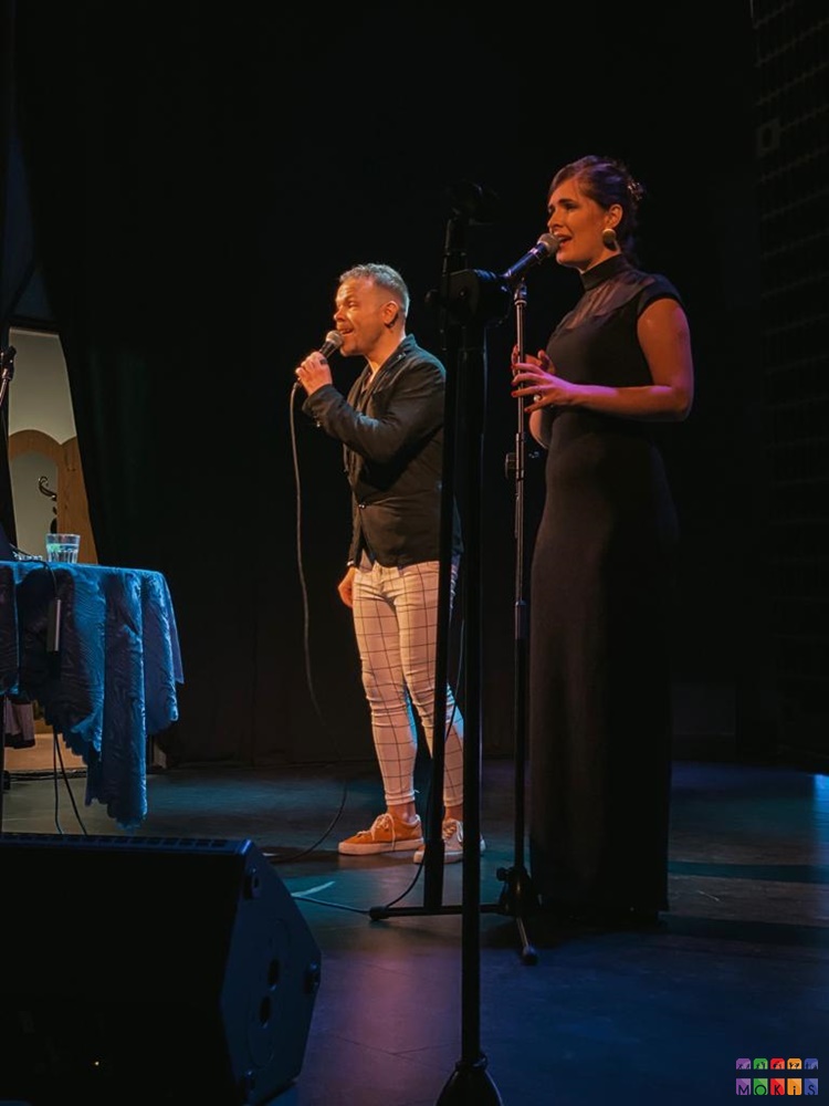 Zdjęcie przedstawiające mężczyznę i kobietę z mikrofonami na scenie.