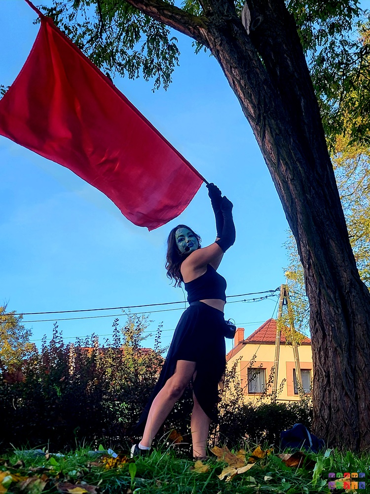 Zdjęcie przedstawiające kobietę wymachującą czerwona flagą w parku