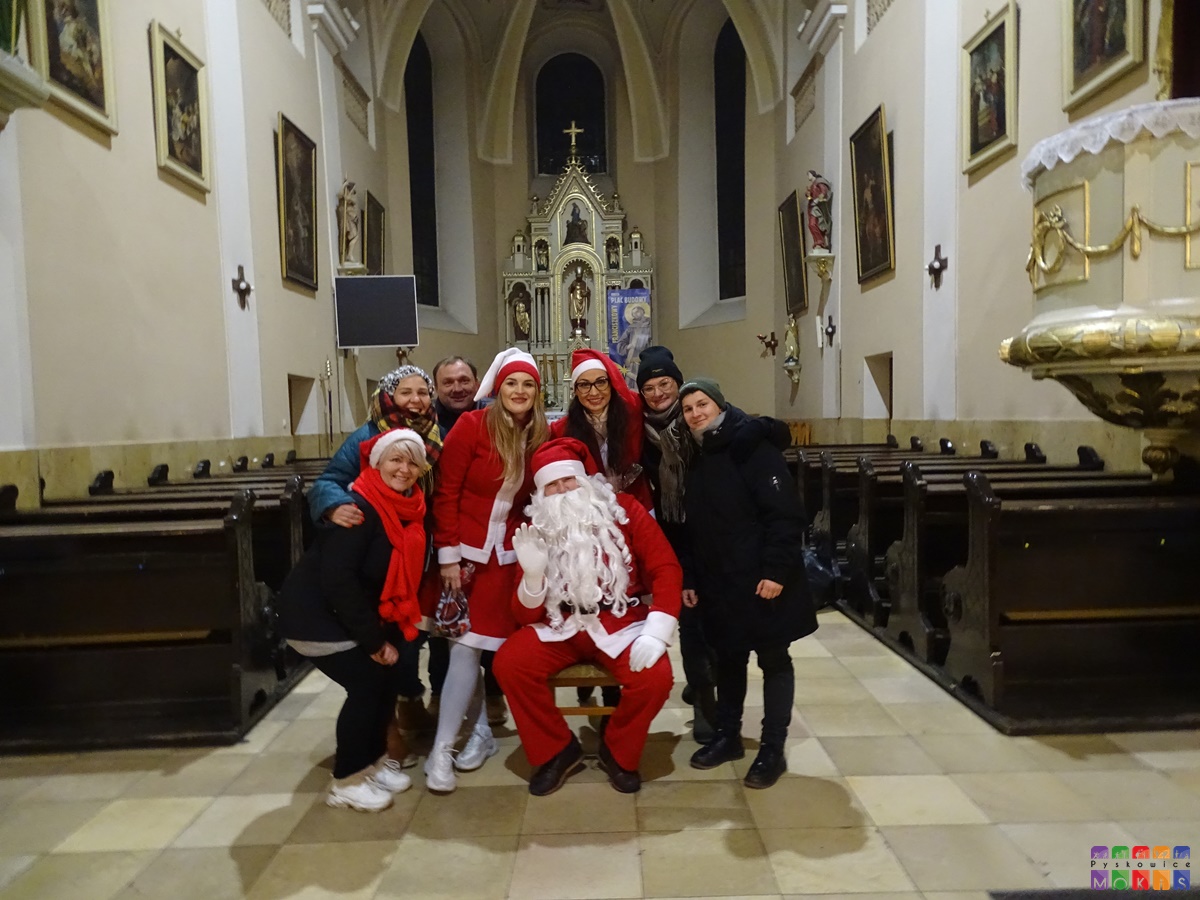 Zdjęcie przedstawiające ustawionych ludzi do wykonania zdjęcia z Mikołajem w wewnątrz kościoła. W tle widać ołtarz