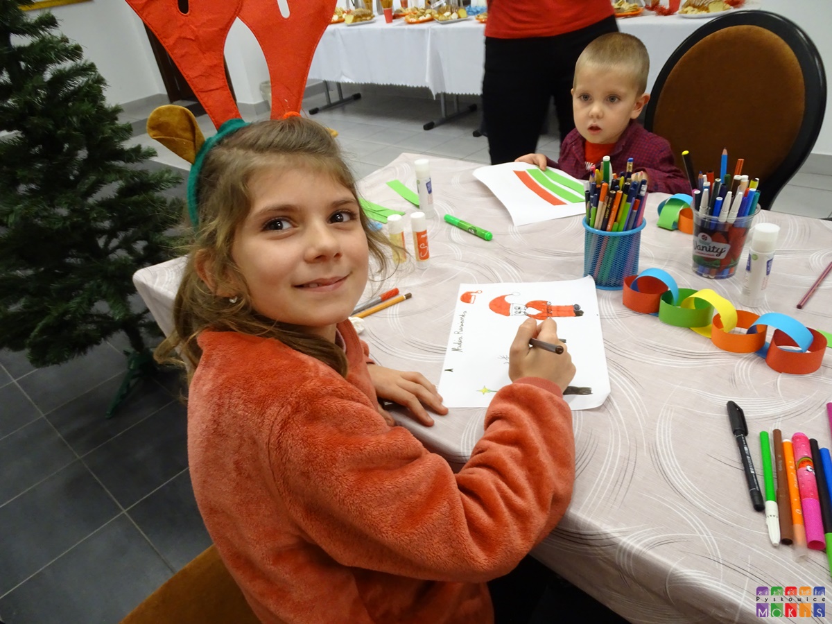 Zdjęcie przedstawiające siedzących dzieci przy stole i rysujących coś na kartkach.