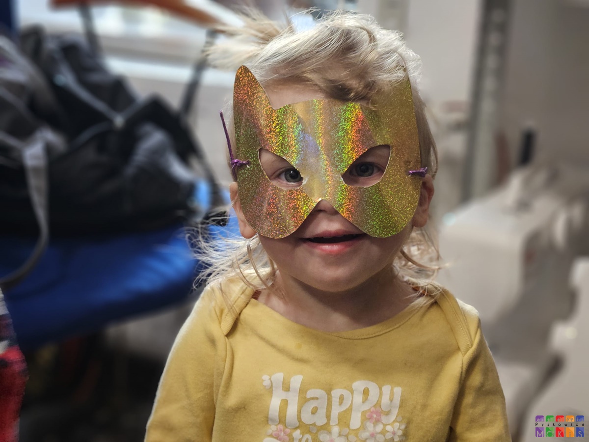 Zdjęcie przedstawiające dziecko w kolorowej masce nałożonej na twarzy. Jest to portret.