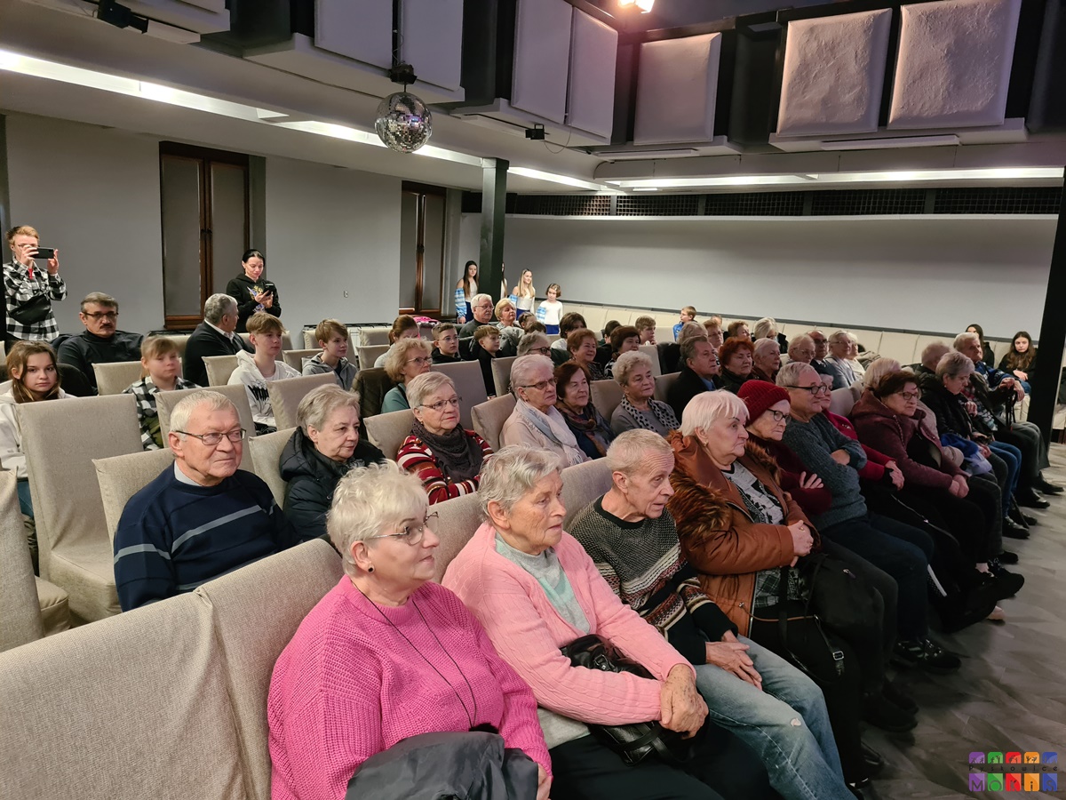 Zdjęcie przedstawia siedzących ludzi na widowni sali widowiskowej MOKiS Pyskowice