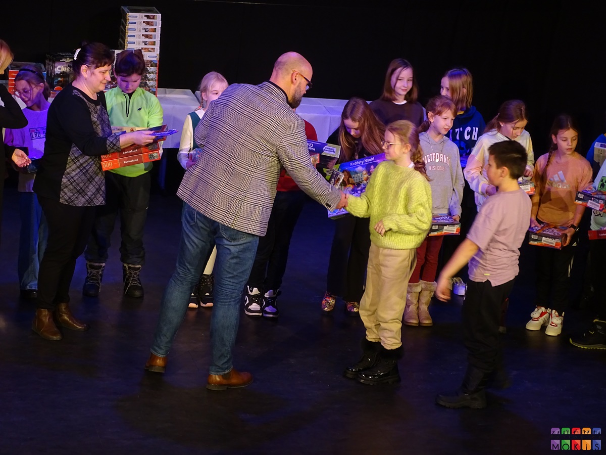 Zdjęcie przedstawiające wręczenie nagród dzieciom na scenie MOKiS-u przez Burmistrza miasta