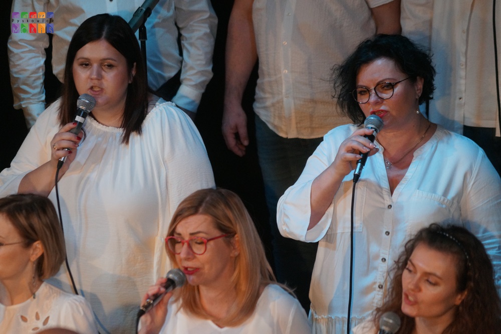 Zdjęcie przedstawia śpiewających ludzi do mikrofonu