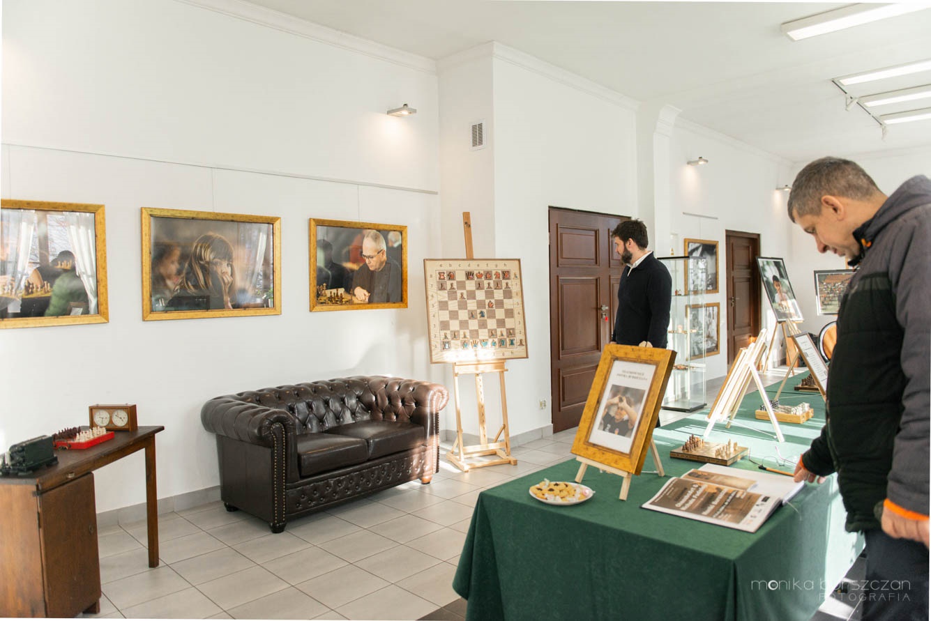 Zdjęcie przedstawia dwóch mężczyzn oglądających wystawę o tematyce szachowej w Centrum Wystawienniczym w Pyskowicach.